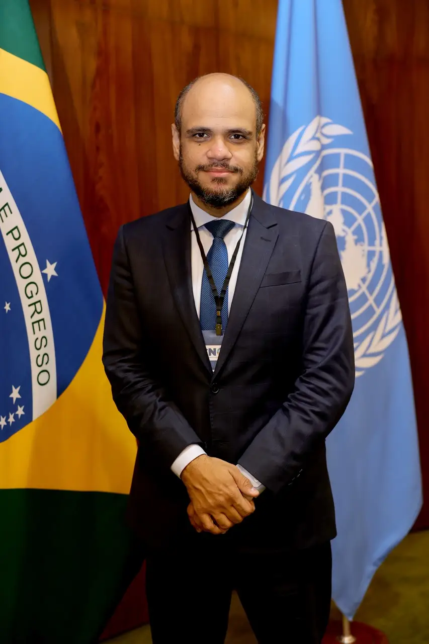 Sóstenes Marchezine junto às bandeiras do Brasil e das Nações Unidas