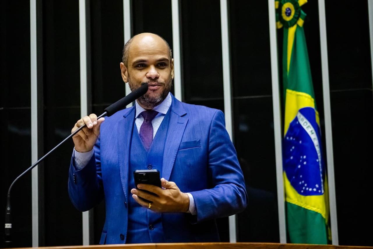 Sóstenes Marchezine participa de pronunciamento no plenário do Congresso Nacional, junto à bandeira brasileira.